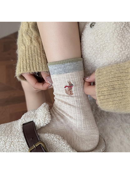 Beige Kangaroo sock worn with a slipper, with hands holding the ribbed leg.