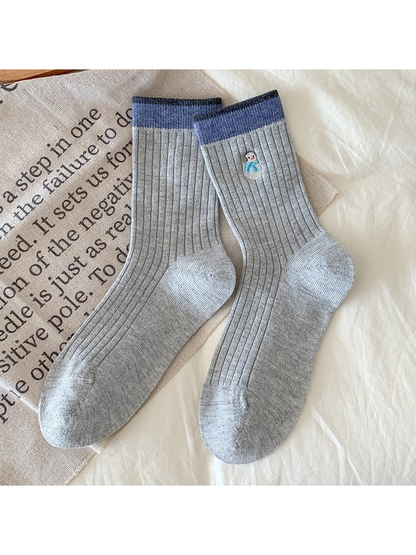 Light gray Snowman socks with ribbing, blue cuffs, and an embroidered snowman with a blue scarf.