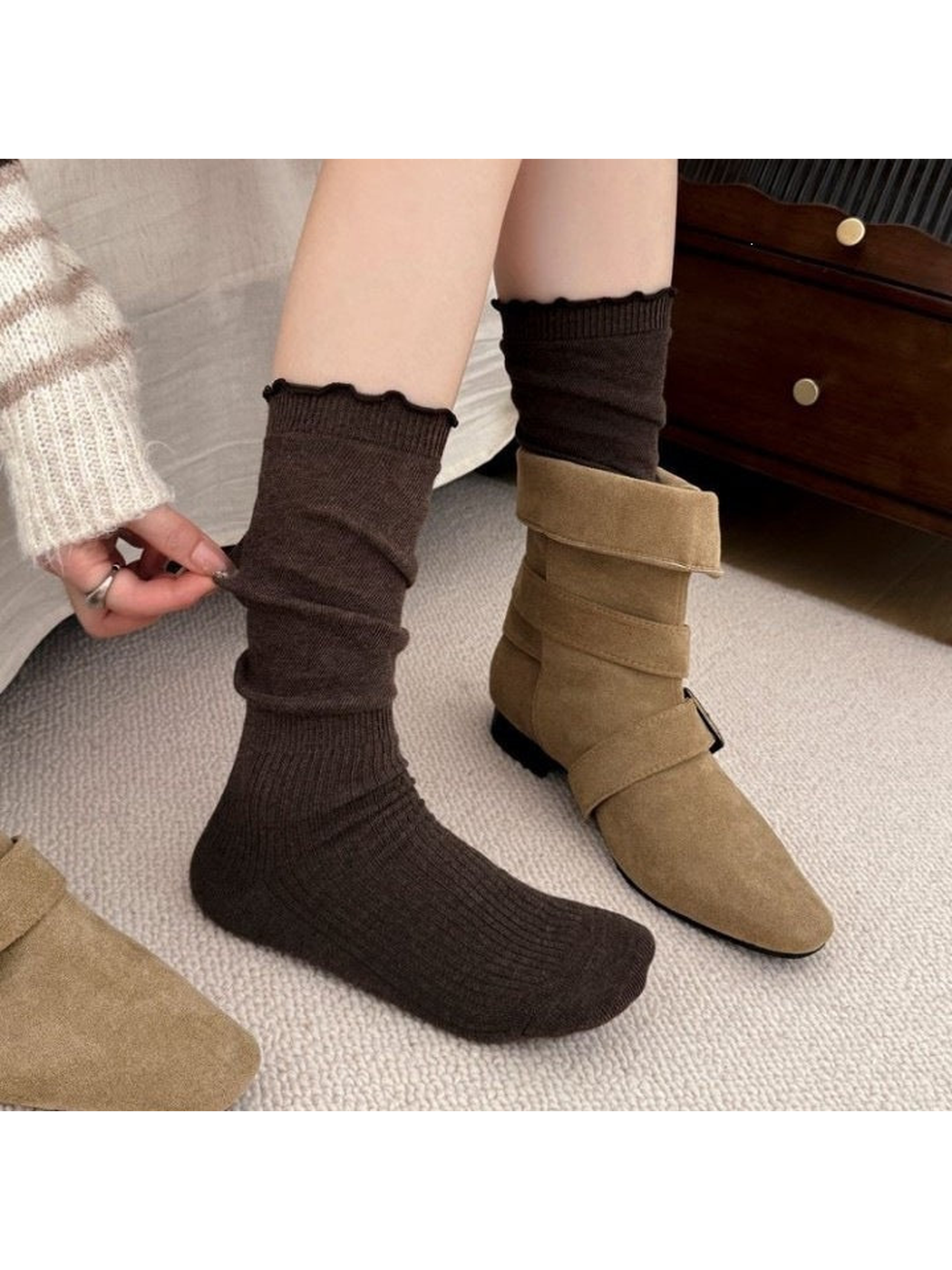 Brown socks worn with one foot uncovered and the other inside a tan boot.