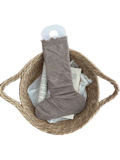 Coffee sock with a ruffled cuff and ribbed ankle and foot displayed in a woven basket.