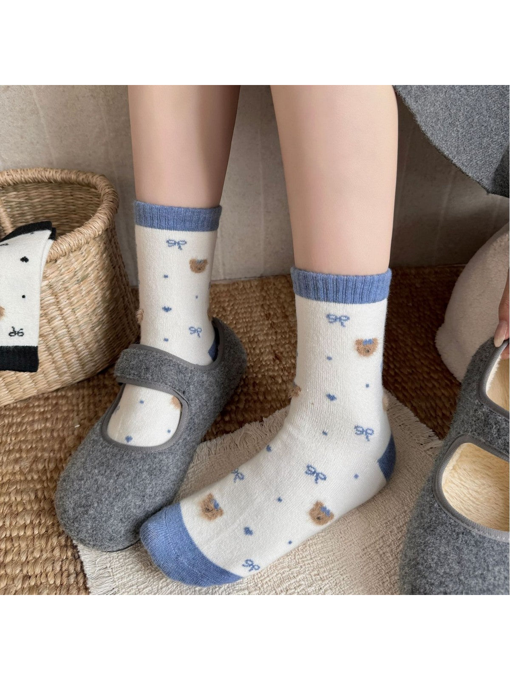 Blue-trim bear-pattern socks worn with one foot in a gray shoe and the other sock fully visible.
