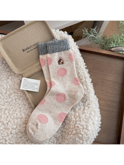 House socks with pink polka dots, a house motif, and gray ribbed cuffs.