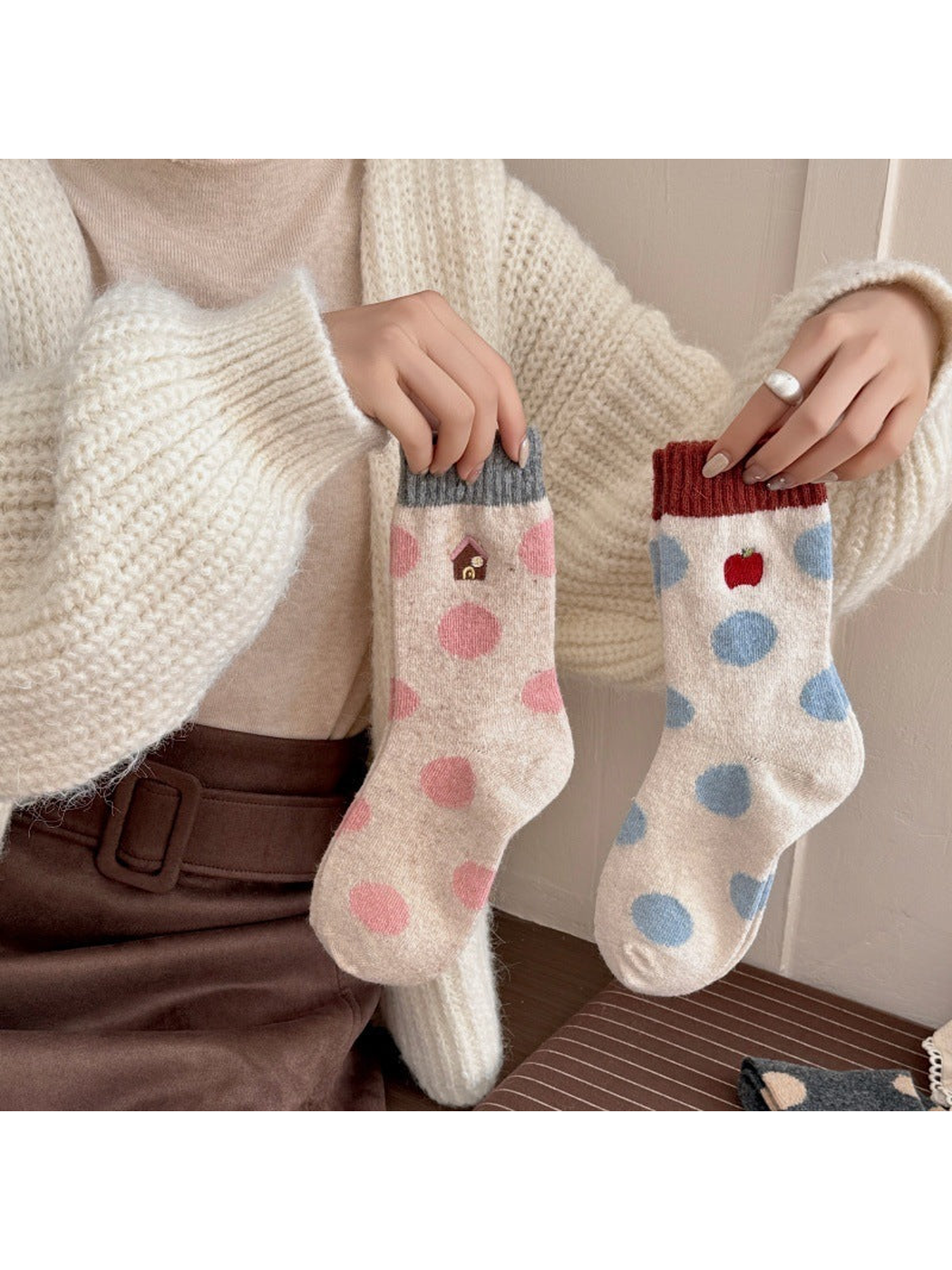 Person holding House and Apple socks with contrasting cuffs and polka dots.