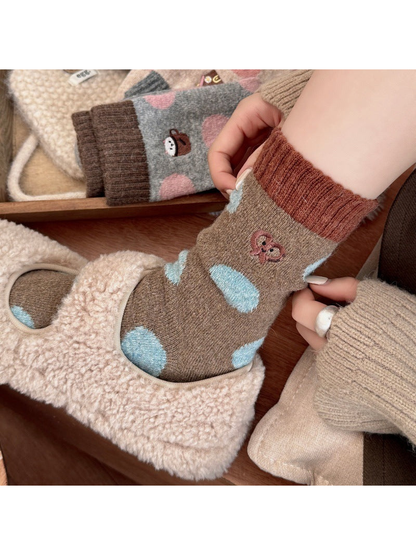 Person adjusting a Pretzel sock with light blue polka dots while wearing a cream slipper.