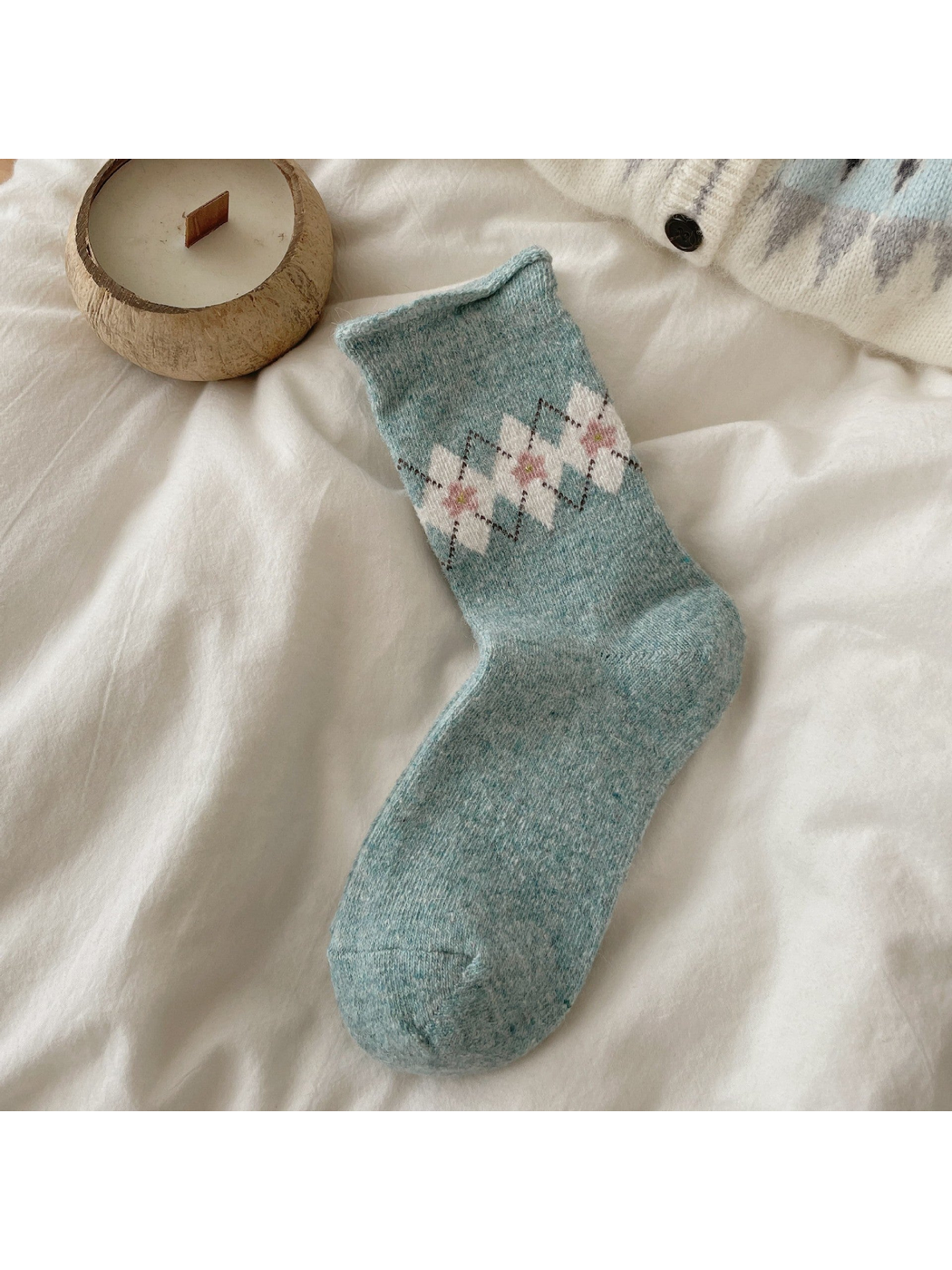 Blue sock with ivory argyle diamonds, pink floral centers, and a rolled cuff.