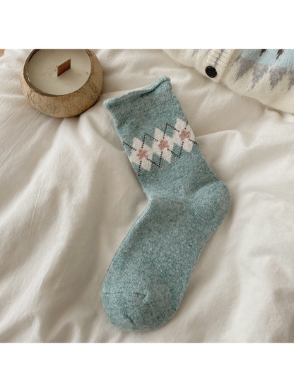 Blue sock with ivory argyle diamonds, pink floral centers, and a rolled cuff.