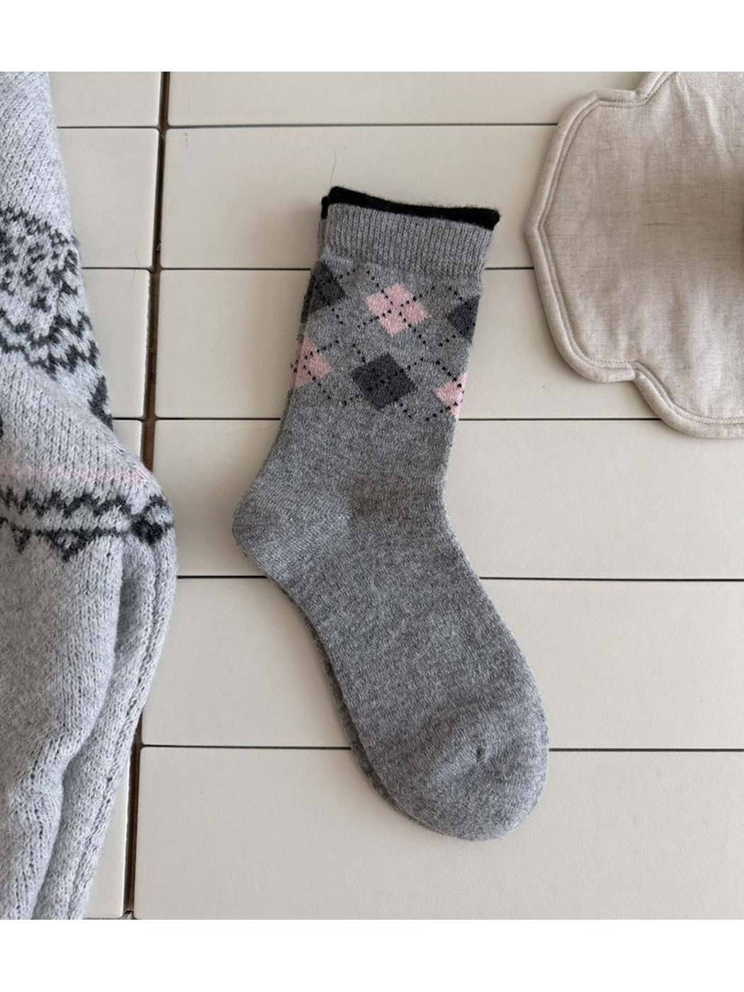 Light Gray sock with pink and dark argyle diamonds, a ribbed cuff and a black top edge.