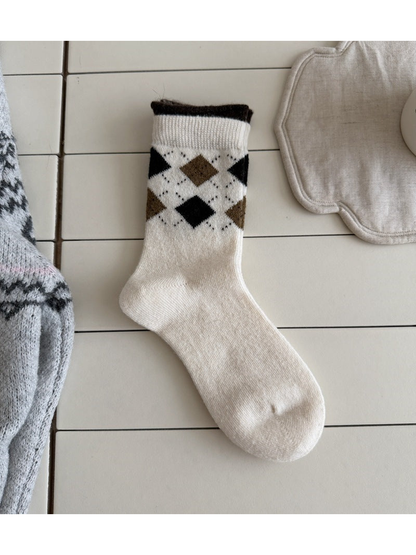 Ivory sock with black and brown argyle diamonds, a ribbed cuff and a dark top edge.