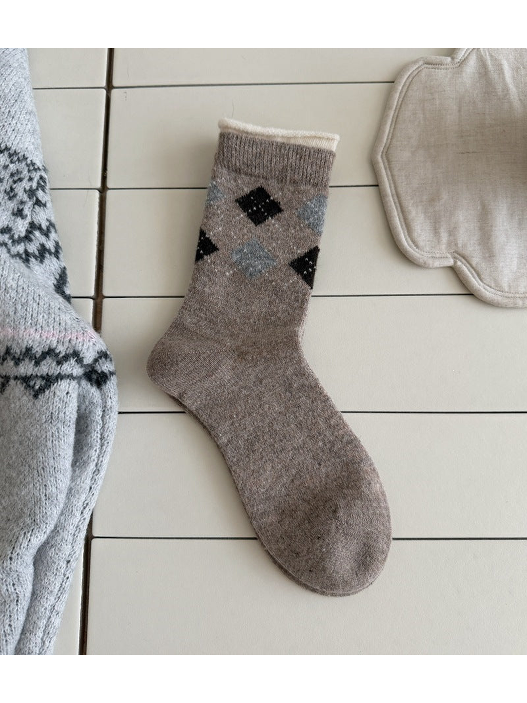 Brown sock with black and pale blue argyle diamonds, a ribbed cuff and a cream top edge.