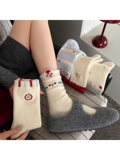 Cat socks worn with gray shoes beside other sock designs, with an Apple sock held in one hand.
