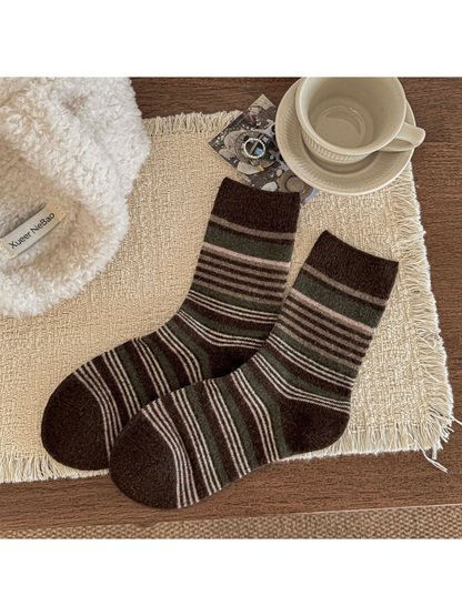 Brown striped crew socks with ribbed cuffs displayed on a woven mat.