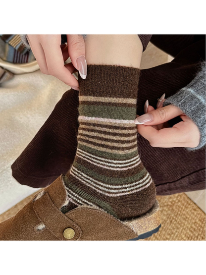 Close-up of brown striped socks being adjusted at the ribbed cuff.