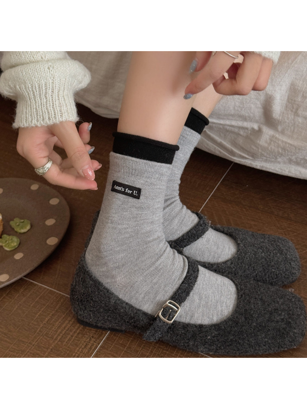 Light Gray socks with black rolled cuffs worn with dark gray buckle-strap shoes.