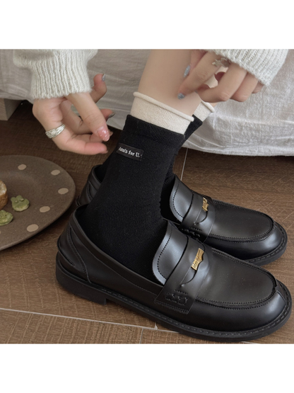 Black socks with ivory rolled cuffs worn with black loafers.