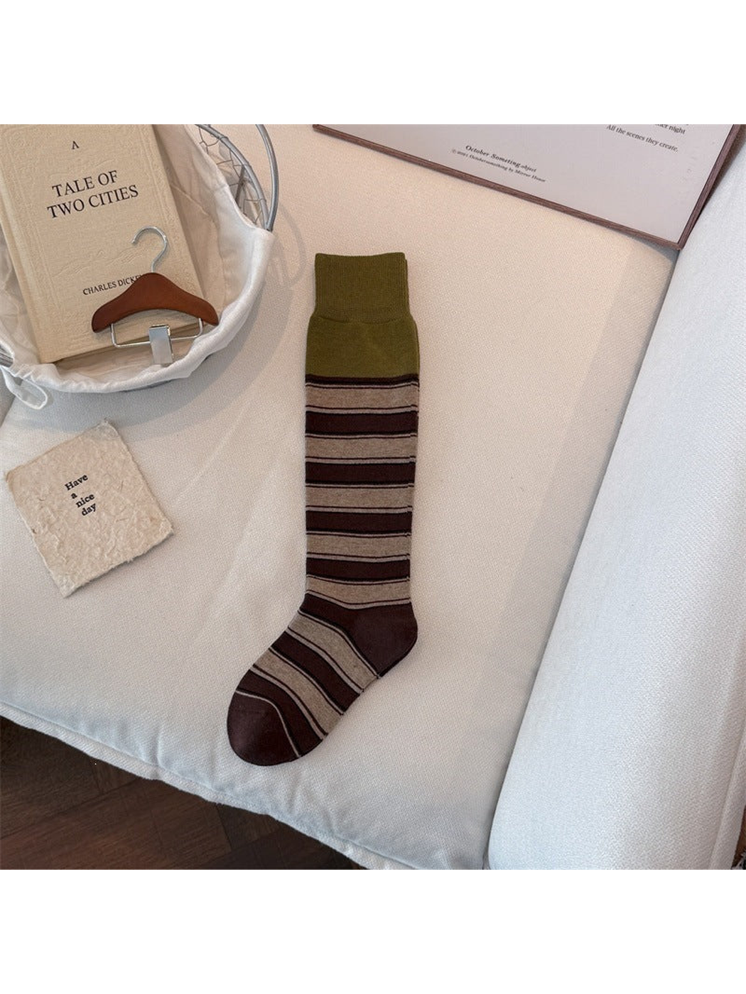 Green sock laid flat with a wide ribbed cuff, brown and beige stripes, and dark brown toe and heel.