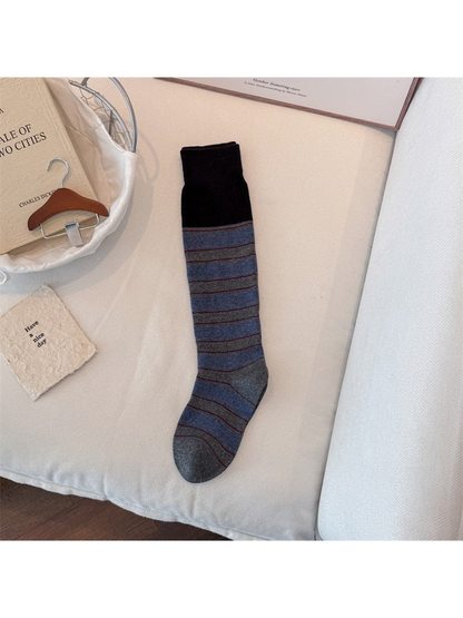 Blue sock laid flat with a black ribbed cuff, horizontal stripes, and gray toe and heel.
