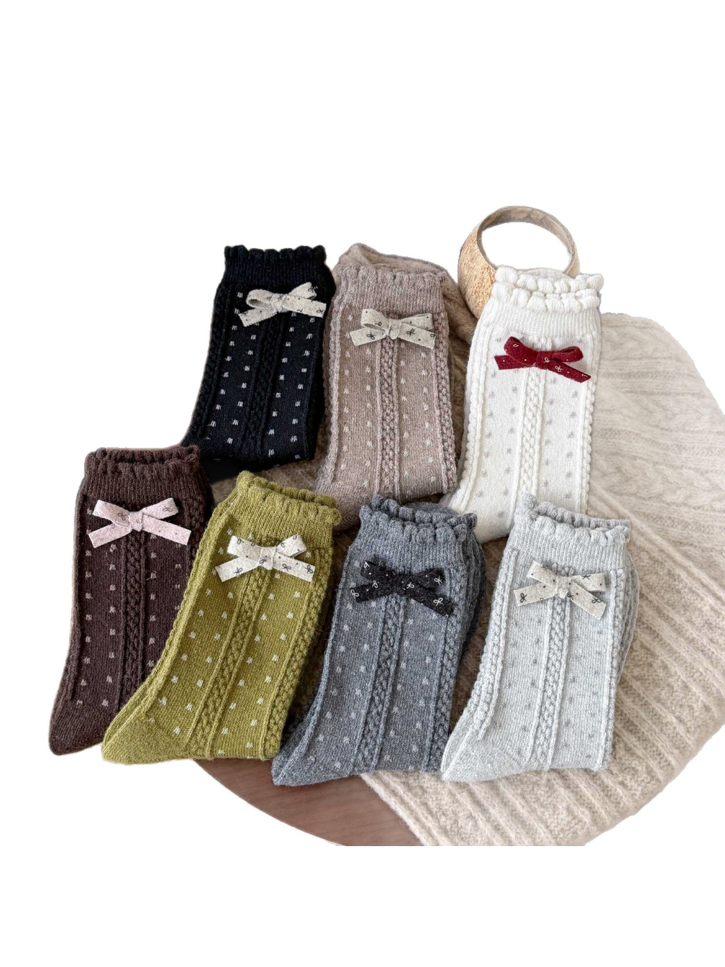 Seven colors of dotted socks with vertical cable-textured bands, scalloped cuffs, and contrasting bows.