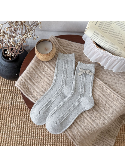 Light Gray dotted socks with cable-textured bands, scalloped cuffs, and a cream bow.