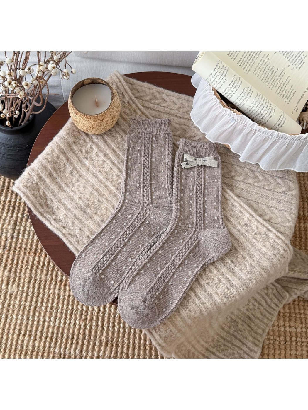 Greige socks with small light dots, cable-textured bands, scalloped cuffs, and a cream bow.
