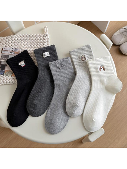 Five ribbed sock styles arranged side by side, showing animal motifs, a bow, and a small label.