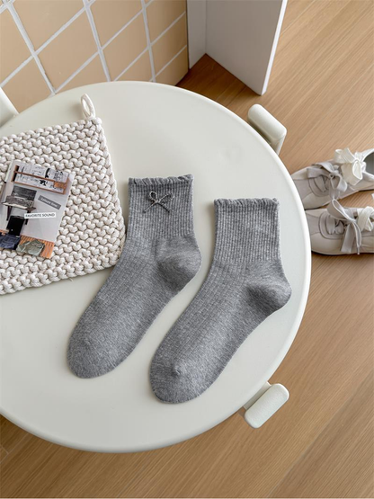 Gray Bow socks with ribbed cuffs and wavy cuff edges arranged on a chair.