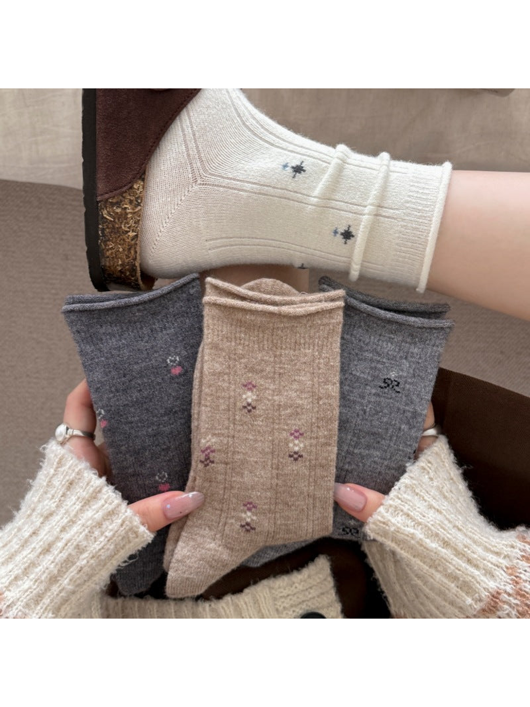 Patterned socks with rolled cuff edges in ivory, beige and gray colorways.