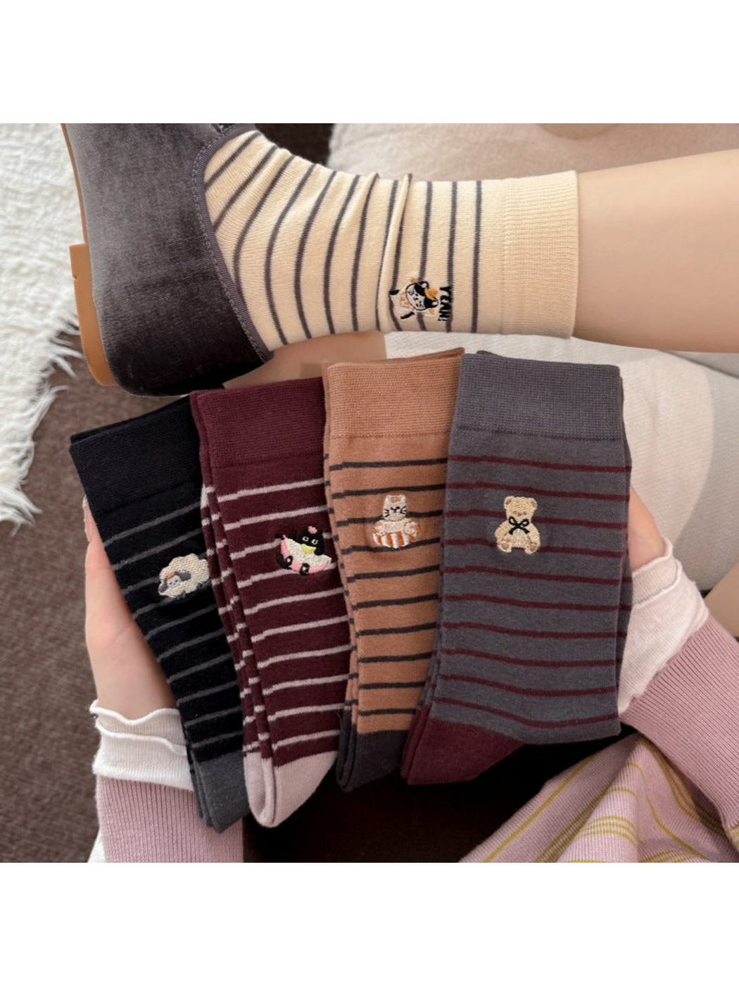 Striped socks with animal motifs held beside an Ivory sock worn with a gray shoe.