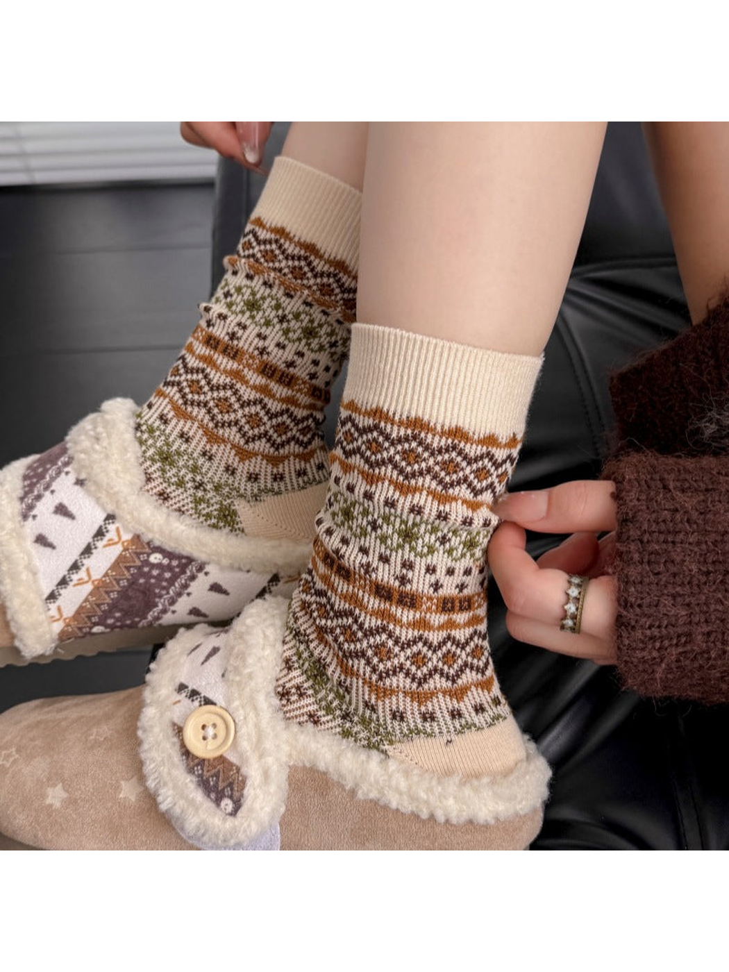 Close-up of Ivory socks with ribbed cuffs and geometric bands worn with slippers.