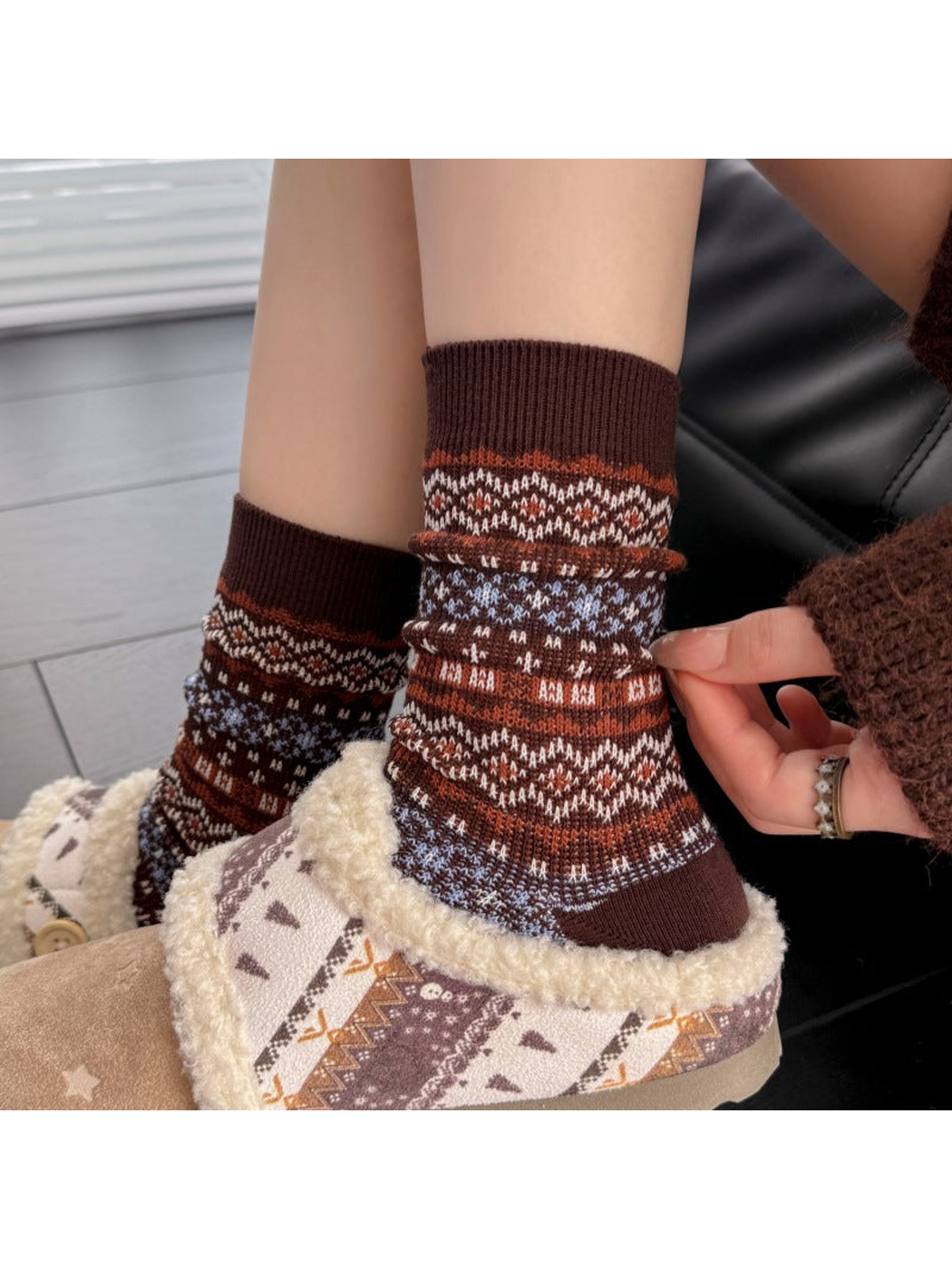 Close-up of Brown socks with ribbed cuffs and geometric bands worn with slippers.