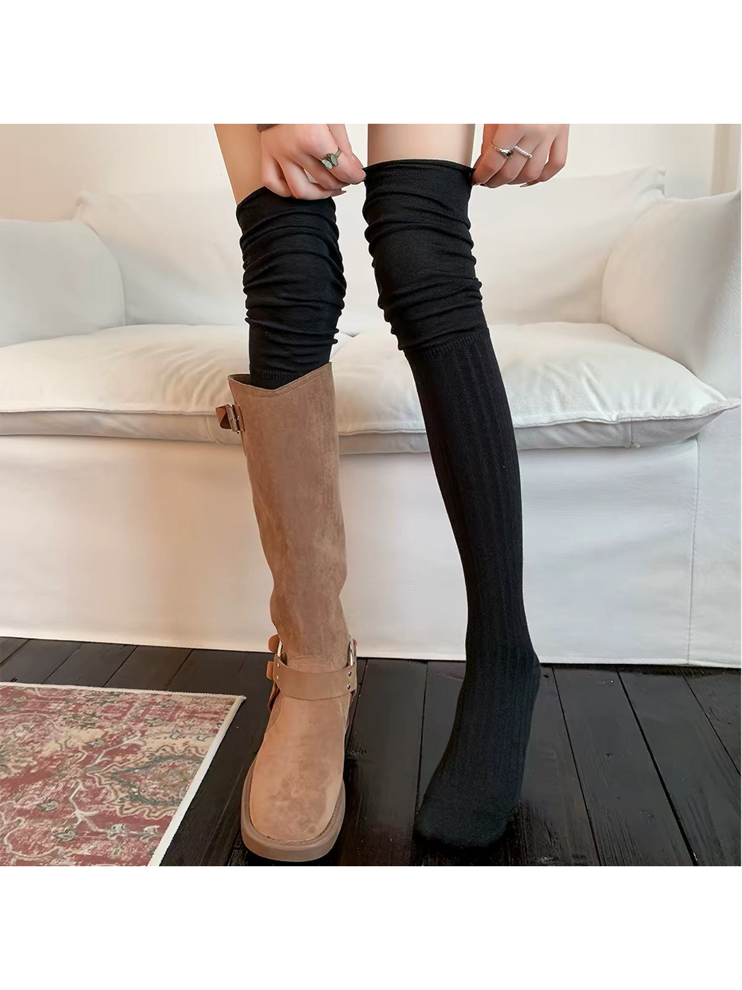 Black socks worn with one brown boot while hands hold the top edge.