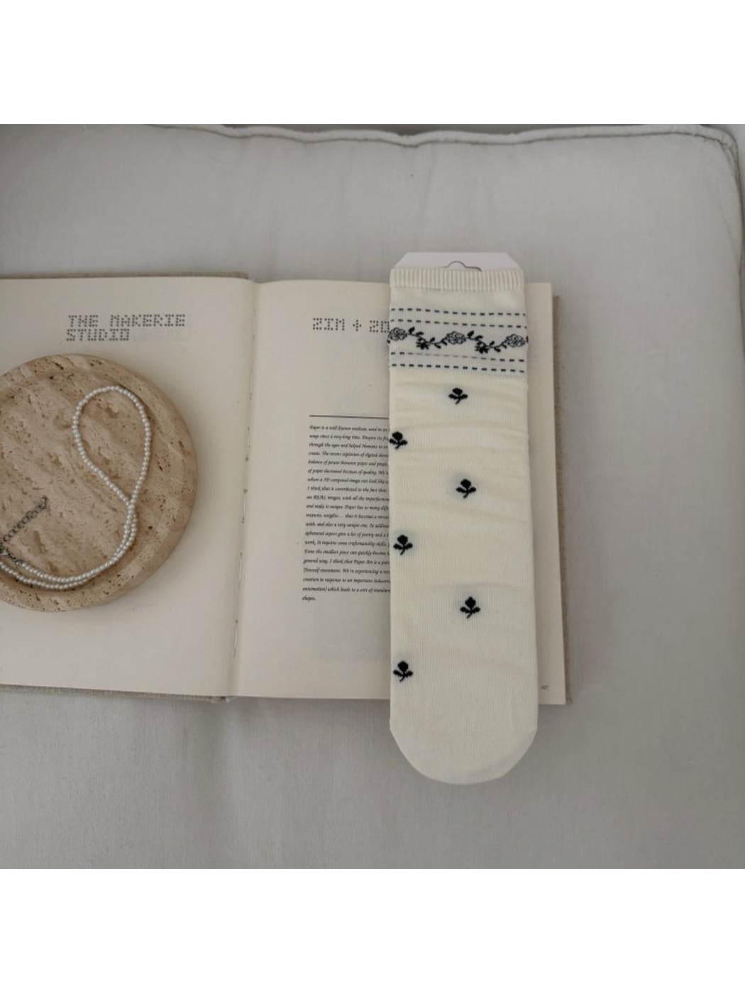 Ivory sock with dark floral sprigs and a patterned ribbed cuff.