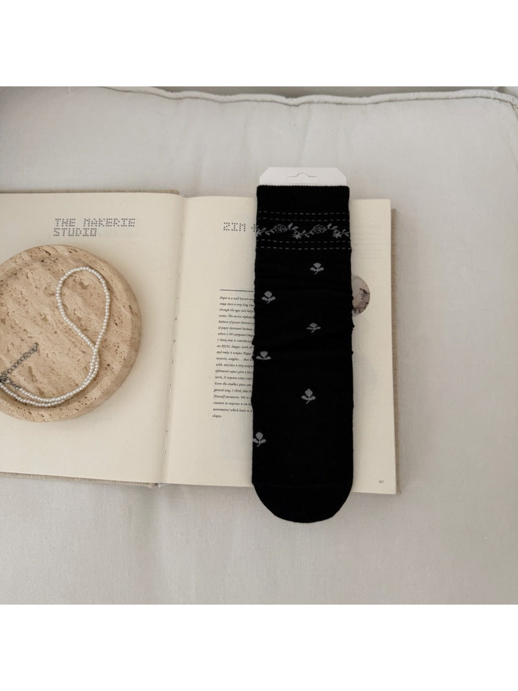 Black sock with light floral sprigs and a patterned ribbed cuff.