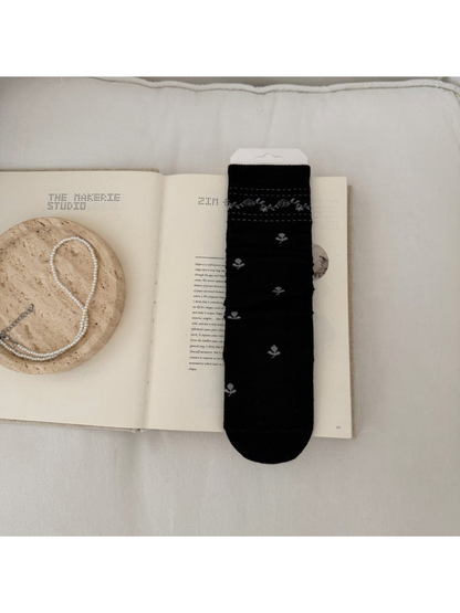 Black sock with light floral sprigs and a patterned ribbed cuff.