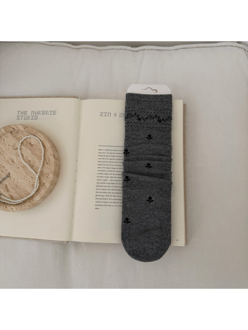 Gray sock with dark floral sprigs and a patterned ribbed cuff.