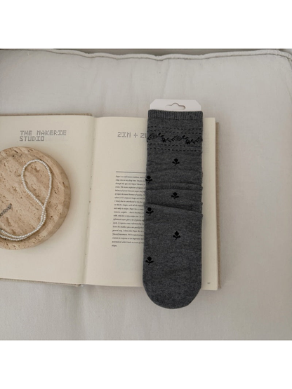 Gray sock with dark floral sprigs and a patterned ribbed cuff.