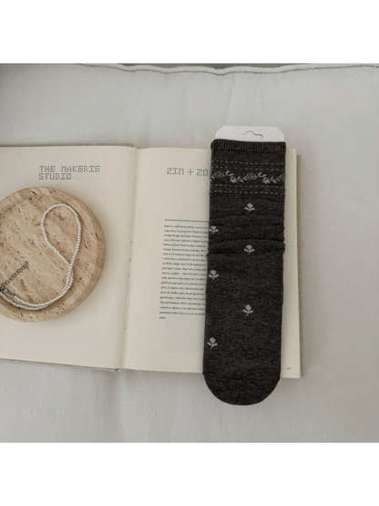 Brown sock with light floral sprigs and a patterned ribbed cuff.