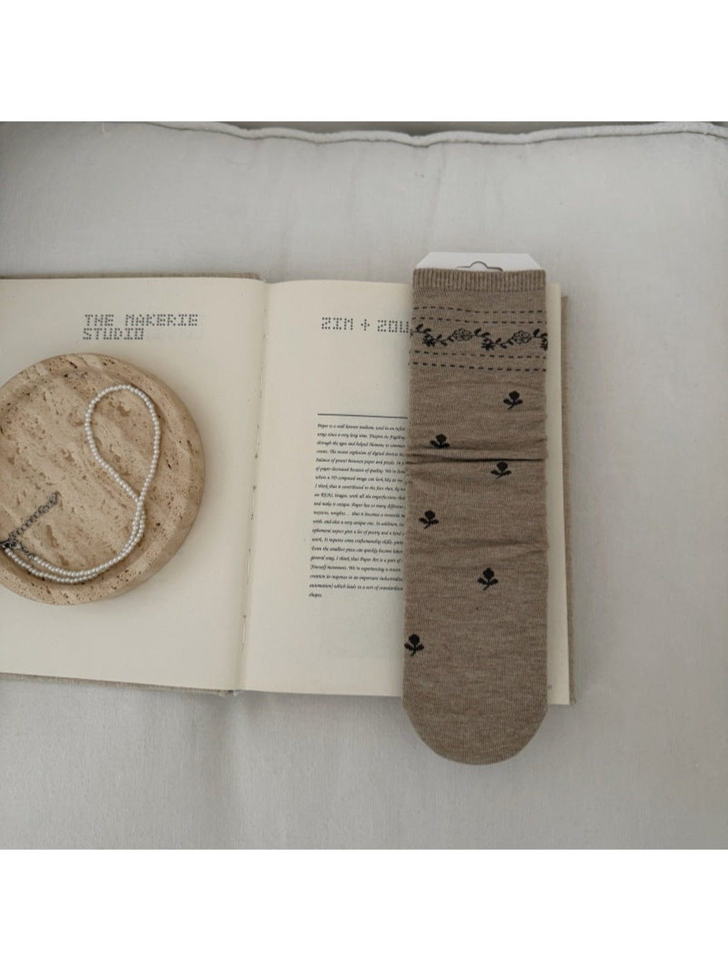 Beige sock with dark floral sprigs and a patterned ribbed cuff.