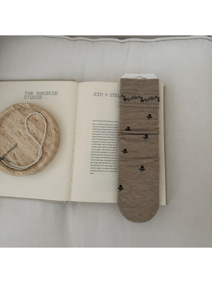 Beige sock with dark floral sprigs and a patterned ribbed cuff.