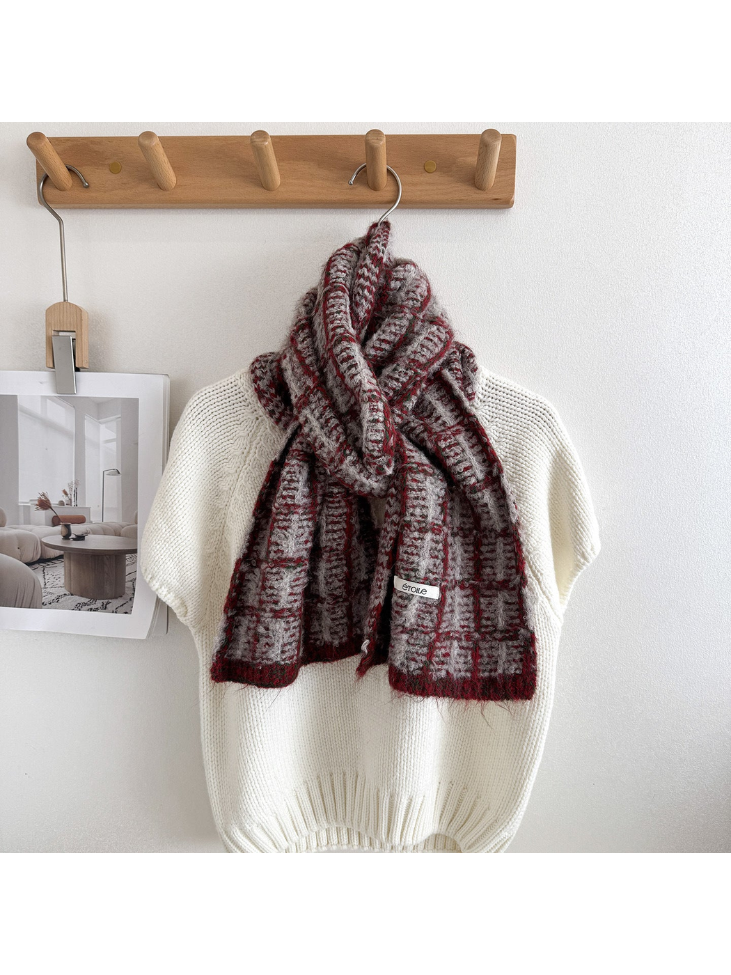 Burgundy plaid scarf looped and draped over a cream knit sweater, showing pale checks and burgundy end borders.