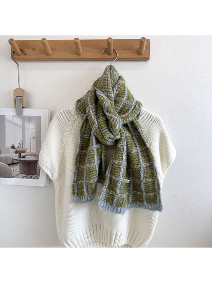 Green plaid scarf looped and draped over a cream knit sweater, with pale blue-gray grid lines and end borders.