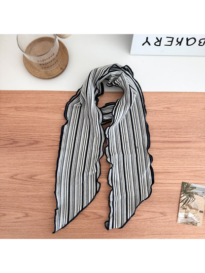 Black striped scarf arranged in a loop with wavy edges and pointed ends.