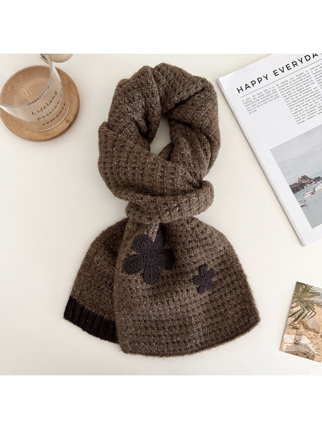 Brown textured scarf arranged in a rounded knot with flower appliqués and contrasting end trim