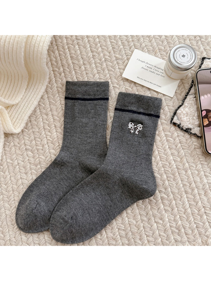 Dark gray socks with a spotted bow motif, dark cuff stripes and ribbed cuffs.