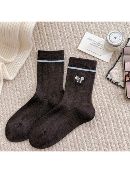 Brown socks with a spotted bow motif, light cuff stripes and ribbed cuffs.