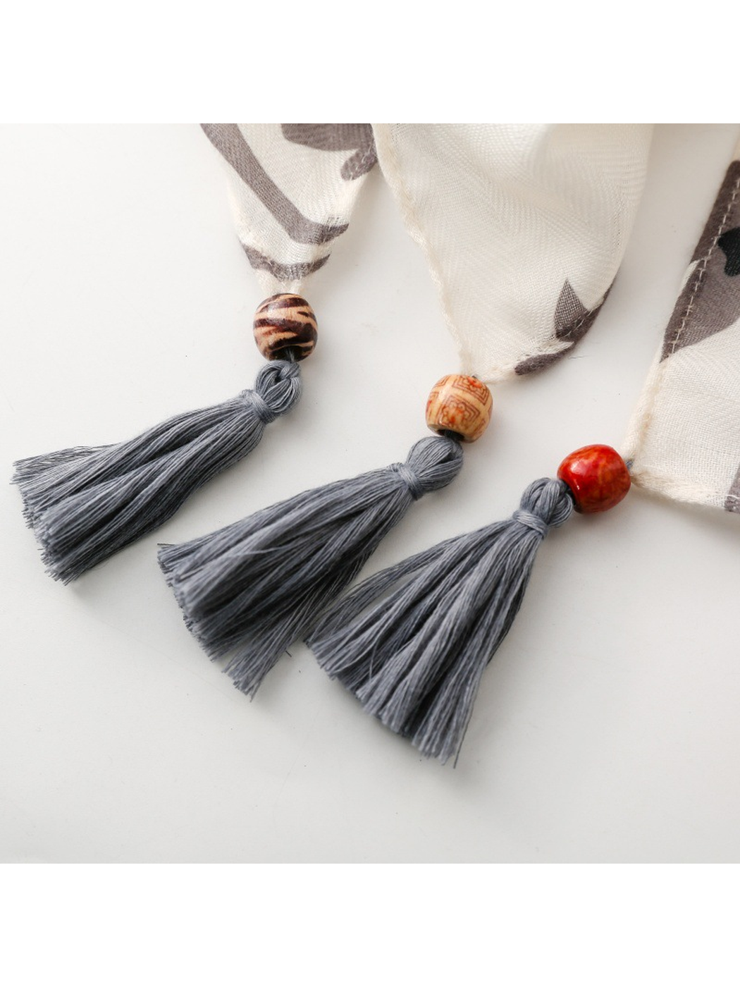 Close-up of three gray scarf tassels with assorted round bead accents