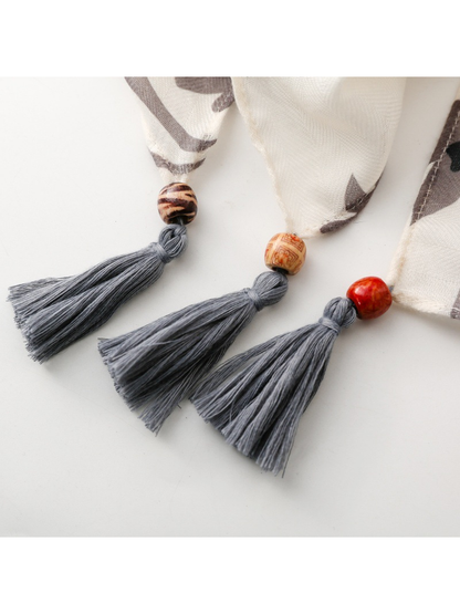 Close-up of three gray scarf tassels with assorted round bead accents