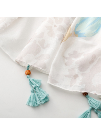 Close-up of aqua tassels and bead accents along the narrow hemmed edge
