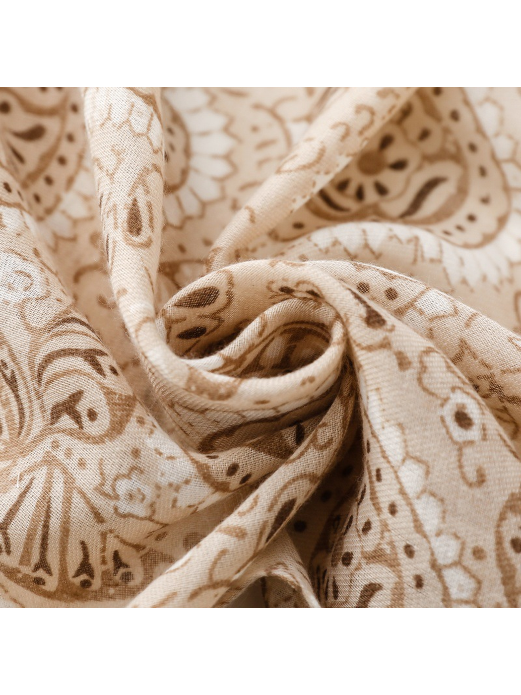 Close-up of the khaki and brown paisley print and fine woven texture in a spiral fold