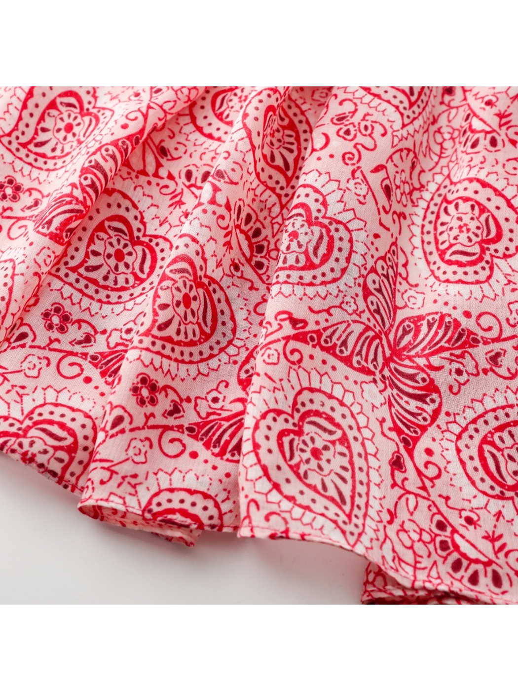 Close-up of the red paisley and butterfly print extending to the narrow stitched hem