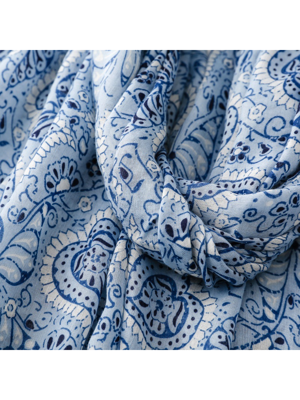 Close-up of the blue paisley scarf print and fine woven texture in looped folds